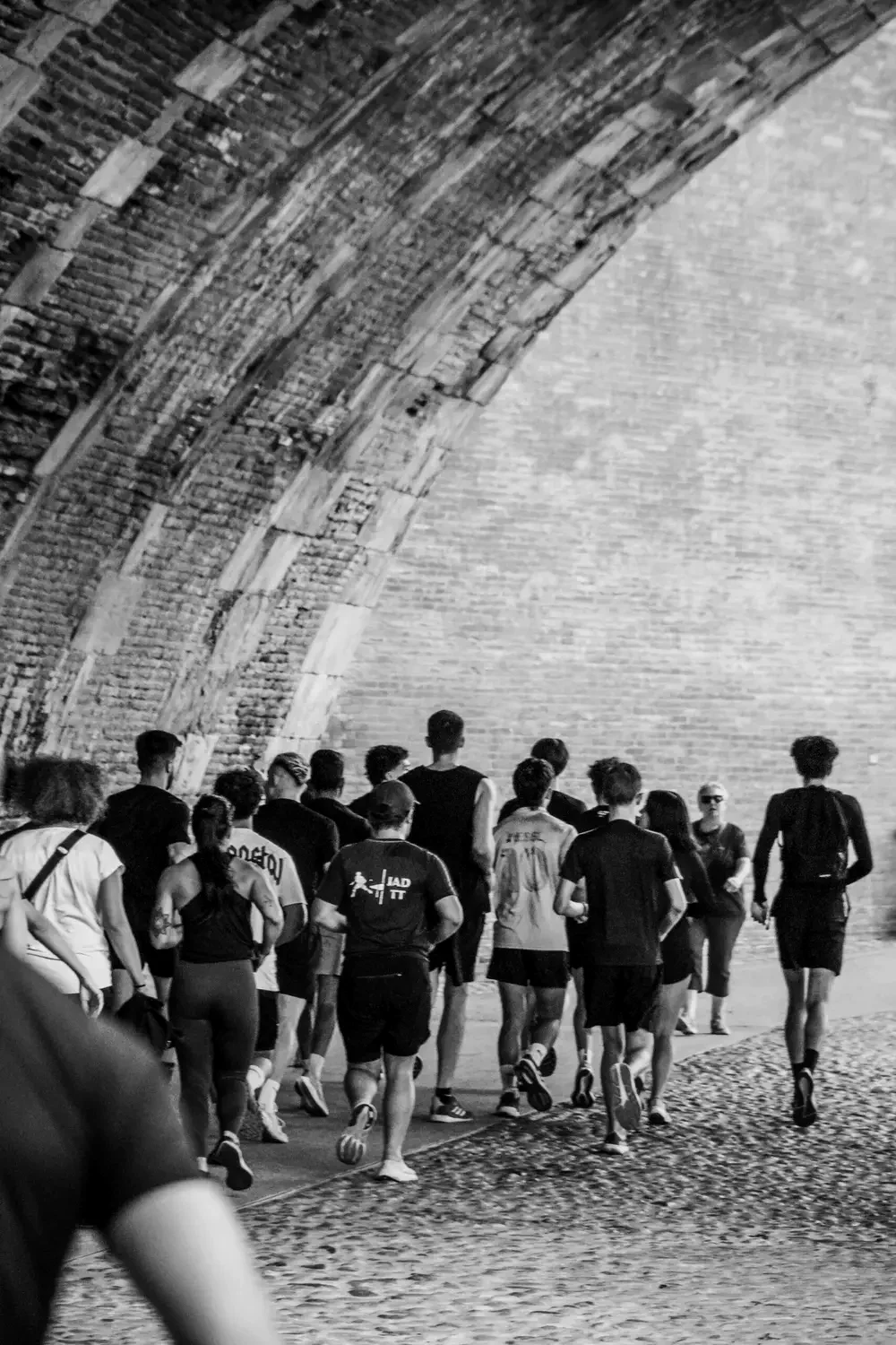 Un run club passe sous une arche de brique à Toulouse